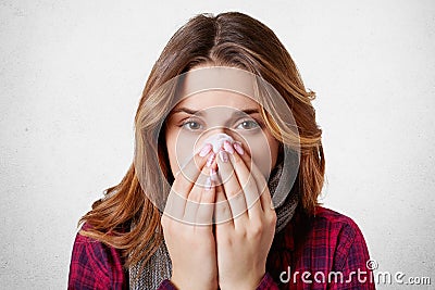 Close up portrait of beautiful woman sneezes and coughs, uses tissue, rubs nose, has bad cold, over white background. Low Stock Photo