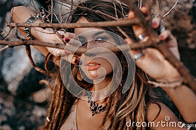 Close up portrait of beautiful young woman looking in camera through dry branches Stock Photo