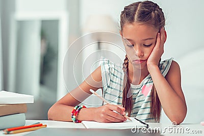 Close-up portrait of bored cute Afro-American girl doing writing homework. Stock Photo