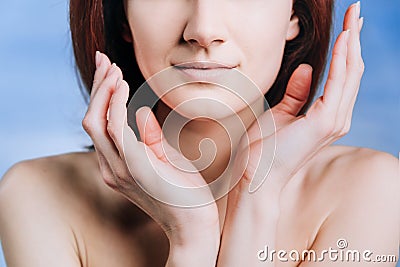 Close-up portrait of calm young white woman holding hands near face: only lips Stock Photo