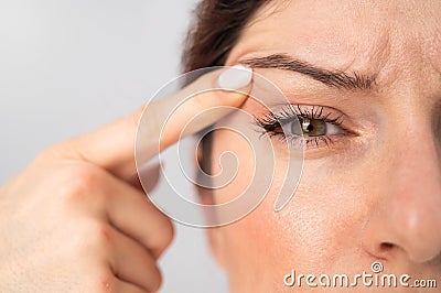 Close-up portrait of Caucasian middle-aged woman pointing to the wrinkles on the upper eyelid. Signs of aging on the Stock Photo