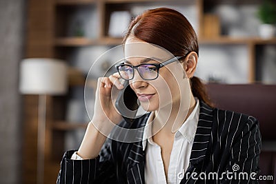 Close up portrait caucasian woman employee in glasses working in office talking on mobile phone Stock Photo