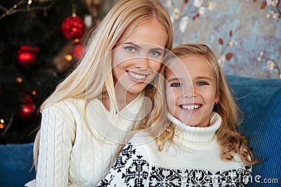 Close-up portrait of charming blonde mother and daughter sitting Stock Photo