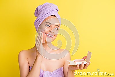 Close-up portrait of charming cheery girl wiping oily skin with napkin isolated over vibrant yellow color background Stock Photo