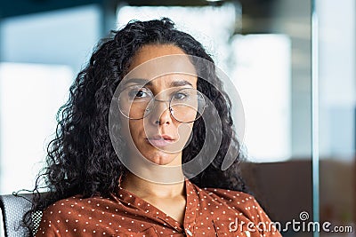 Close-up portrait of confident serious business woman, hispanic woman wearing glasses inside office looking at camera Stock Photo