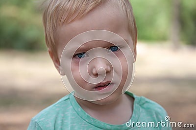 Close up portrait of cute caucasian baby boy with serious expression in blue eyes. Stock Photo