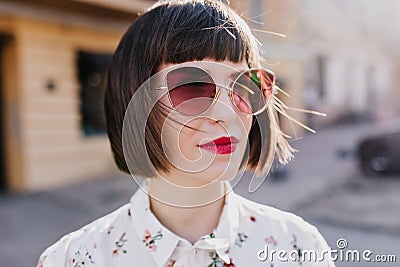 Close-up portrait of dreamy white woman with short hair standing on the street. Outdoor photo of pleasant caucasian Stock Photo