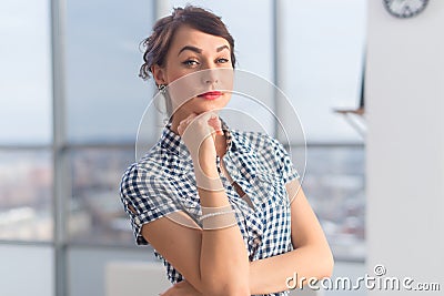 Close-up portrait of an elegant ambitious young woman, holding arms crossed, wearing checkered shirt. Stock Photo