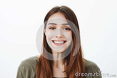 Close-up portrait of friendly charming european brunette with broad positive smile, standing over gray background Stock Photo