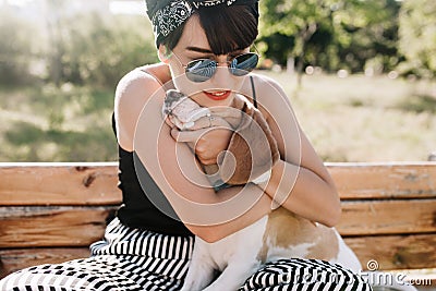 Close-up portrait of glad brunette lady embracing her beagle dog with gently smile. Outdoor photo of happy girl in Stock Photo