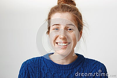 Close-up portrait of good-looking girl with freckles and natural red hair smiling nervously and chuckling, talking with Stock Photo