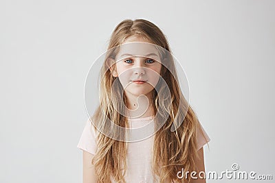 Close up portrait of good-looking young girl with blond hair in pink dress, looking in camera with calm expression Stock Photo