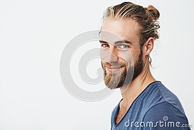 Close up portrait of handsome manly guy with beard posing in three quarters, looking in camera and happily smiling Stock Photo