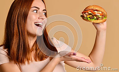 Close up portrait of a hungry young woman eating burger isolated over nude background Stock Photo