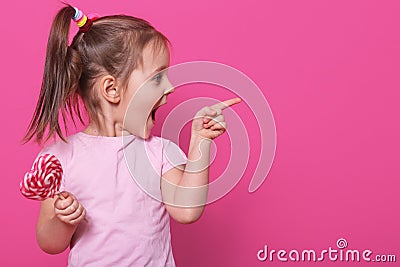 Close up portrait of little attractive child opening mouth widely, looking other side with excitement, holding heart bright Stock Photo