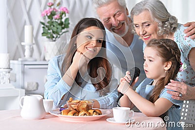 Close up portrait of little girl singing karaoke with mother and grandparents Stock Photo
