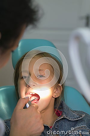 Close up portrait of a little smiling girl at dentist office. Dentist examining little girl's teeth in clinic. people, medicine, Stock Photo