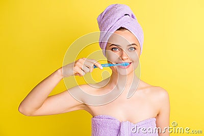 Close-up portrait of lovely naked girl wearing turban cleansing teeth isolated over vibrant yellow color background Stock Photo