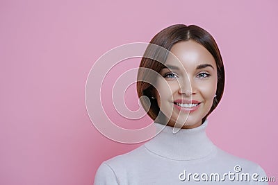 Close up portrait of lovely satisfied joyful woman with dark hair, smiles pleasantly, shows white teeth, wears poloneck, isolated Stock Photo