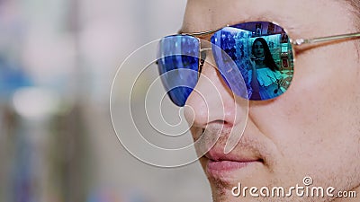 close-up, portrait of man in blue sunglasses at optical store. in spectacles is reflected the showcase of optics and Stock Photo