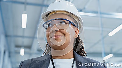 Close Up Portrait of a Middle Aged, Happy Black Female Engineer Putting On a White Hard Hat, While Stock Photo