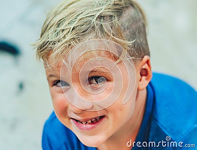 Close up portrait mischievous cute blond side looking blue eyed boy making freckles face play laughing in happy mood Stock Photo