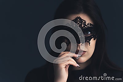 Close-up portrait of a mysterious attractive woman with theatrical mask over dark background Stock Photo