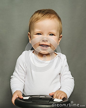 Close-up portrait of a nine-month-old baby girl with blond hair and blue eyes, dressed in a white bodysuit on a gray background Stock Photo