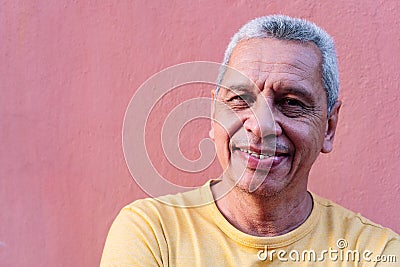 Close up portrait older Hispanic man leaning against wall and staring Stock Photo