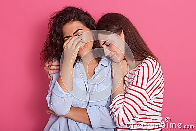 Close up portrait of one woman crying and another embracing her and calming down, female wearing blue shirt having problems, cries Stock Photo