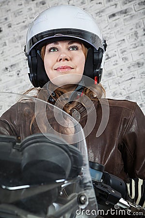 Close-up portrait of pretty motorcyclist in open helmet sitting on the motorbike Stock Photo