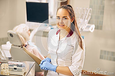 Charming European dentist in blue gloves sitting in the clinic Stock Photo