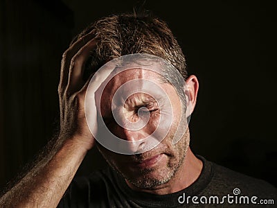 Close up portrait of sad and depressed man with hand on face looking desperate feeling frustrated and helpless crying miserable in Stock Photo