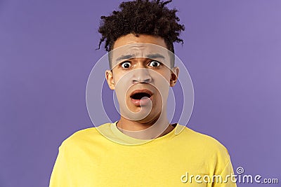 Close-up portrait of shocked, alarmed young man gasping, open mouth scared and frightened, staring camera concerned Stock Photo