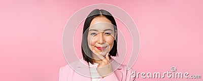 Close up portrait of smiling asian working lady in suit, businesswoman looking thoughtful, thinking or deciding smth Stock Photo