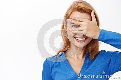 Close up portrait of smiling happy woman covers her eyes, peeks through fingers, intrigued by surprise, stands over Stock Photo
