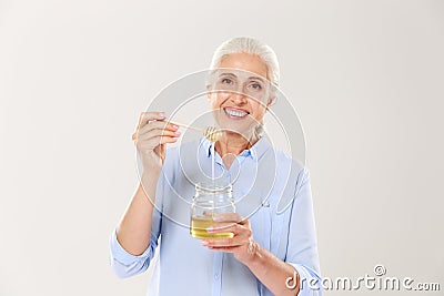 Close-up portrait of smiling old woman, holding honey jar with s Stock Photo