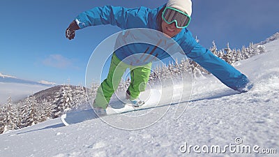 CLOSE UP, PORTRAIT: Smiling snowboarder doing hand drag in fresh powder snow Stock Photo