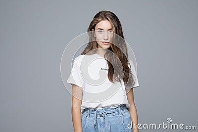 Portrait of smiling young woman in white t-shirt looking at camera, isolated on gray background Stock Photo