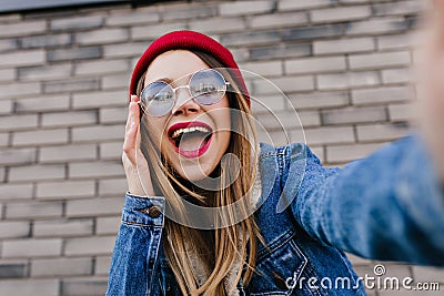 Close-up portrait of stunning blonde lady in denim jacket making selfie with smile. Photo of joyful Stock Photo