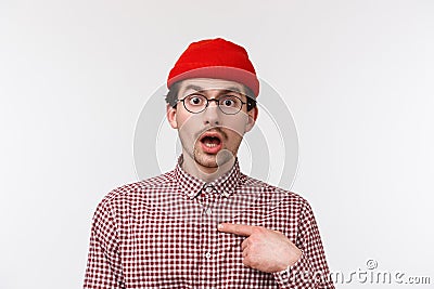 Close-up portrait surprised young hipster guy in glasses and beanie staring with disbelief, pointing himself indecisive Stock Photo