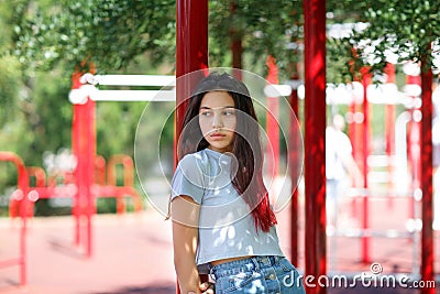A close-up of a young girl in casual clothes on a blurred athletic field background. Fashion, urban, youth concept. Copy space. Stock Photo