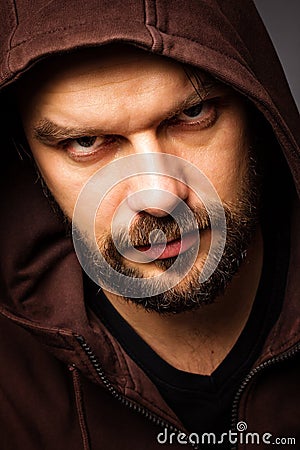 Close-up portrait of threatening man with beard wearing a hood Stock Photo