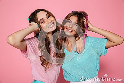 Close-up portrait of two smiling woman dressed like children touching their hair, looking at camera Stock Photo