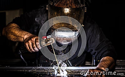 Close up portrait view of professional mask protected welder man welding metal and sparks metal Stock Photo