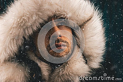 Close up portrait of a white man dressed with an eskimo jacket in the snow Stock Photo
