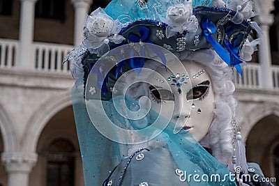 Close up portrait of woman in beautiful blue costume, hat and mask at the Doges Palace, Venice, during the carnival Editorial Stock Photo