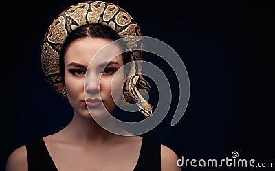 Close up portrait of woman with snake around her head on dark ba Stock Photo