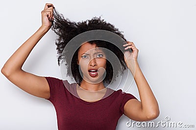 Close up young african woman pulling bad curly hair and looking worried Stock Photo