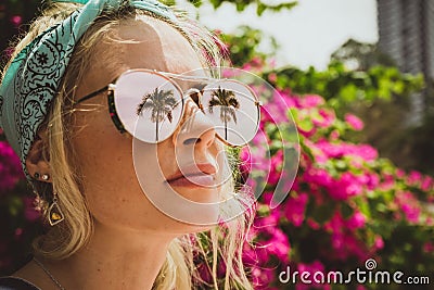 Close-up portrait of a young beautiful girl in glasses with reflection of tropical palms. Summer rest. Modern tourist Stock Photo